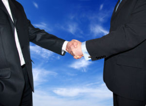 Men are shaking hands on a sky background.